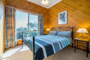 een slaapkamer met een bed en een groot raam bij Freycinet Panorama in Coles Bay