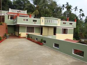 a house with a large driveway in front of it at Green Villa in Virajpet