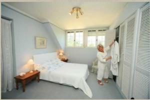 a woman standing in a bedroom with a bed at Résidence Clairbois, Chambres d'Hôtes in Fère-en-Tardenois