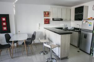 cocina con nevera, mesa y sillas en Apartamento Moderno con Piscina Rodadero, en Santa Marta