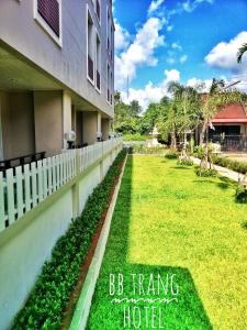 un edificio con una valla y un patio verde en BB Trang Hotel en Trang