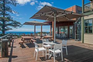 a wooden deck with tables and chairs and umbrellas at Tathra Hotel & Motel in Tathra