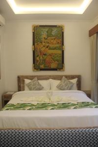 a bedroom with a bed with a painting on the wall at Green Studio Apartment Seminyak in Seminyak +28 photos