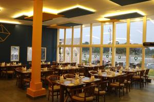 a dining room with tables and chairs and windows at BigStay Apart Hotel in Tada