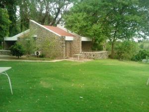 a brick house with a table and a grass yard at Hotel Kailas in Ellora