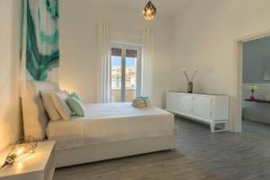 a white bedroom with a bed and a dresser and a window at Spacebility City - self check-in in Cagliari