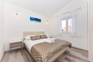 ein weißes Schlafzimmer mit einem Bett und einem Fenster in der Unterkunft Apartments Ana Vrsi in Vrsi