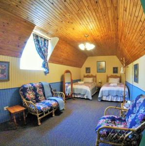 um quarto com duas camas e cadeiras num quarto em A Pilgrims Rest em Graskop
