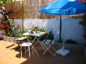 una mesa, sillas y una sombrilla en el patio en Casa Alentejana, en São Teotónio