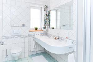 a white bathroom with a sink and a toilet at Hotel Garni Schöne Aussichten in Klöch +38 photos