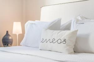 Bett mit weißen Kissen mit dem Wort Ausreden in der Unterkunft Eneos Kythnos Beach Villas-Elegant and Comfort Villas in Kythnos