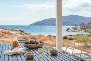 a wooden table with a bowl of fruit and a view of the ocean at Eneos Kythnos Beach Villas-Elegant and Comfort Villas in Kithnos