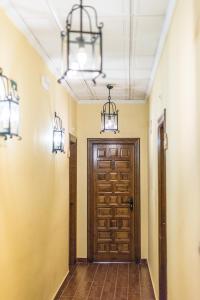 a hallway with a wooden door and two lights at Cortijo De Tajar in Huétor-Tájar
