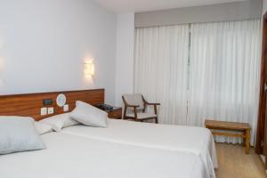 a hotel room with two beds and a chair at Hotel Brisa in A Coruña