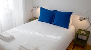 uma cama com uma almofada azul em cima em Cacilhas Guest Apartments em Almada