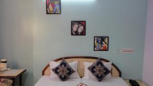 a bedroom with a bed with pillows and pictures on the wall at Hotel Swarajya Palace in Agra