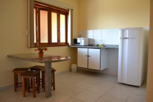 a small kitchen with a table and a refrigerator at Pousada Vento Sul in Ilhabela