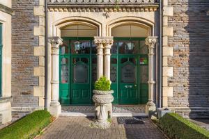 a green door of a building with a plant in front at Lincoln House Private Hotel in Cardiff