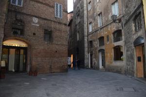 un callejón en un viejo edificio con una persona caminando a través de él en siena centro, civetta, en Siena
