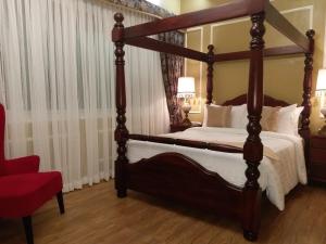 a bedroom with a four poster bed and a red chair at Lee Boutique Hotel Tagaytay in Tagaytay