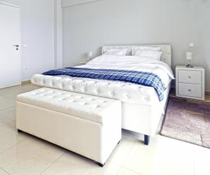 ein weißes Bett mit einer weißen Ottomane im Schlafzimmer in der Unterkunft Villa Nafplio in Nafplio