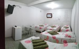 a room with four beds and a table with chairs at Pousada Casagrande - São João in Volta Redonda