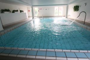 a large indoor swimming pool with blue water at Residenz Albatros in Cuxhaven