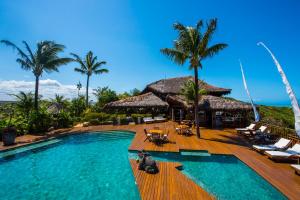 a pool at a resort with a cat sitting on the deck at Hotel Sombra e Água Fresca in Pipa