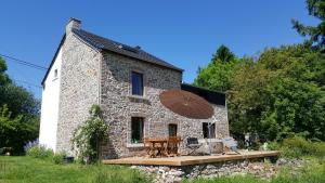 a stone house with a table and chairs and an umbrella at Au calme in Marchin