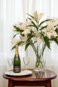 einen Tisch mit einer Flasche Champagner und einer Vase Blumen in der Unterkunft Lincoln House Private Hotel in Cardiff