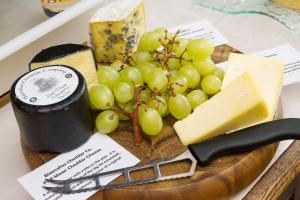 a plate of cheese and grapes on a cutting board at Lincoln House Private Hotel in Cardiff