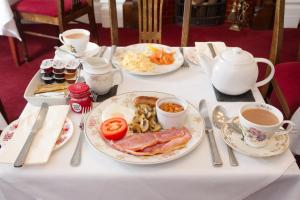 Lincoln House Private Hotel في كارديف: طاولة مع أطباق من الطعام وأكواب من القهوة