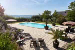 einen Pool mit Stühlen und Sonnenschirmen in der Unterkunft Hotel Garni Schöne Aussichten in Klöch