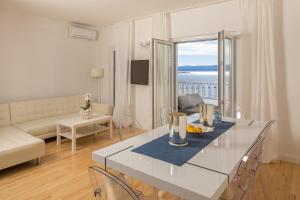 ein weißes Wohnzimmer mit einem Tisch und einem Sofa in der Unterkunft Apartments Villa Lux in Dugi Rat