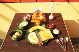 a wooden table topped with eggs and breakfast foods at Kathmandu Village House in Kathmandu