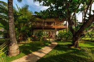 a house with palm trees in front of it at Paradise Beach House in Imbassai