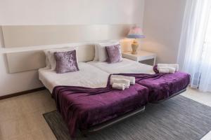 a bedroom with two beds with purple covers and a lamp at Casa Areal de Santa Barbara in Ribeira Grande