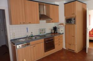 uma pequena cozinha com armários de madeira e um lavatório em Am Kurpark 1a _ 5 em Baabe