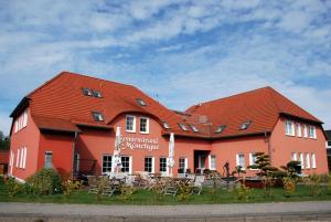 a large red building with tables and chairs in front of it at Das kleine Hotel auf Mönchgut in Lobbe