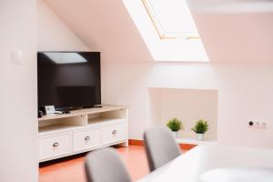 uma sala de estar com uma televisão de ecrã plano num armário branco em Nexus Apartmenthotel em Hévíz