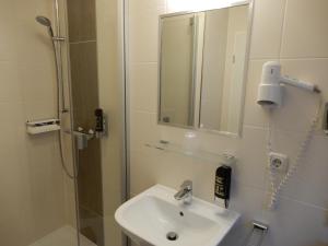 a bathroom with a sink and a shower with a mirror at Hotel Pension Am Hafen in Norddeich