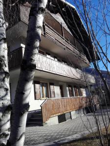un edificio con un balcón de madera y un árbol en Chalet Bianco, en Valdidentro