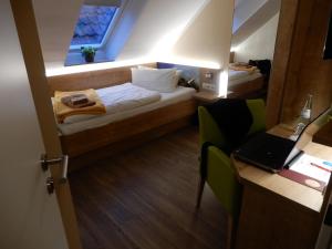 ノルトダイヒにあるHotel Pension Am Hafenのベッド1台、ノートパソコン付きのデスクが備わる小さな客室です。