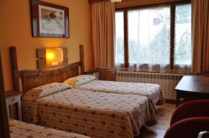 a hotel room with two beds and a window at Hotel Prats in Ribes de Freser