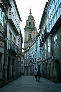 dos personas caminando por una calle con una torre del reloj en Apartamento Bed&Center 2A, en Lugo