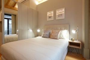 een slaapkamer met een groot wit bed met 2 lampen bij LOFT Sá de Noronha in Porto
