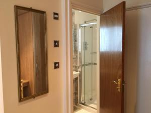 uma casa de banho com um espelho e uma porta de vidro em Albro House Hotel em Londres