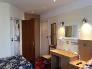 um quarto com uma cama, um lavatório e um espelho em Albro House Hotel em Londres