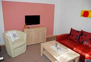 a living room with a red couch and a tv at Ferienwohnungen am Heideweg in Baabe