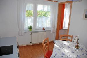 a dining room with a table and chairs and windows at Ferienwohnungen am Heideweg in Baabe